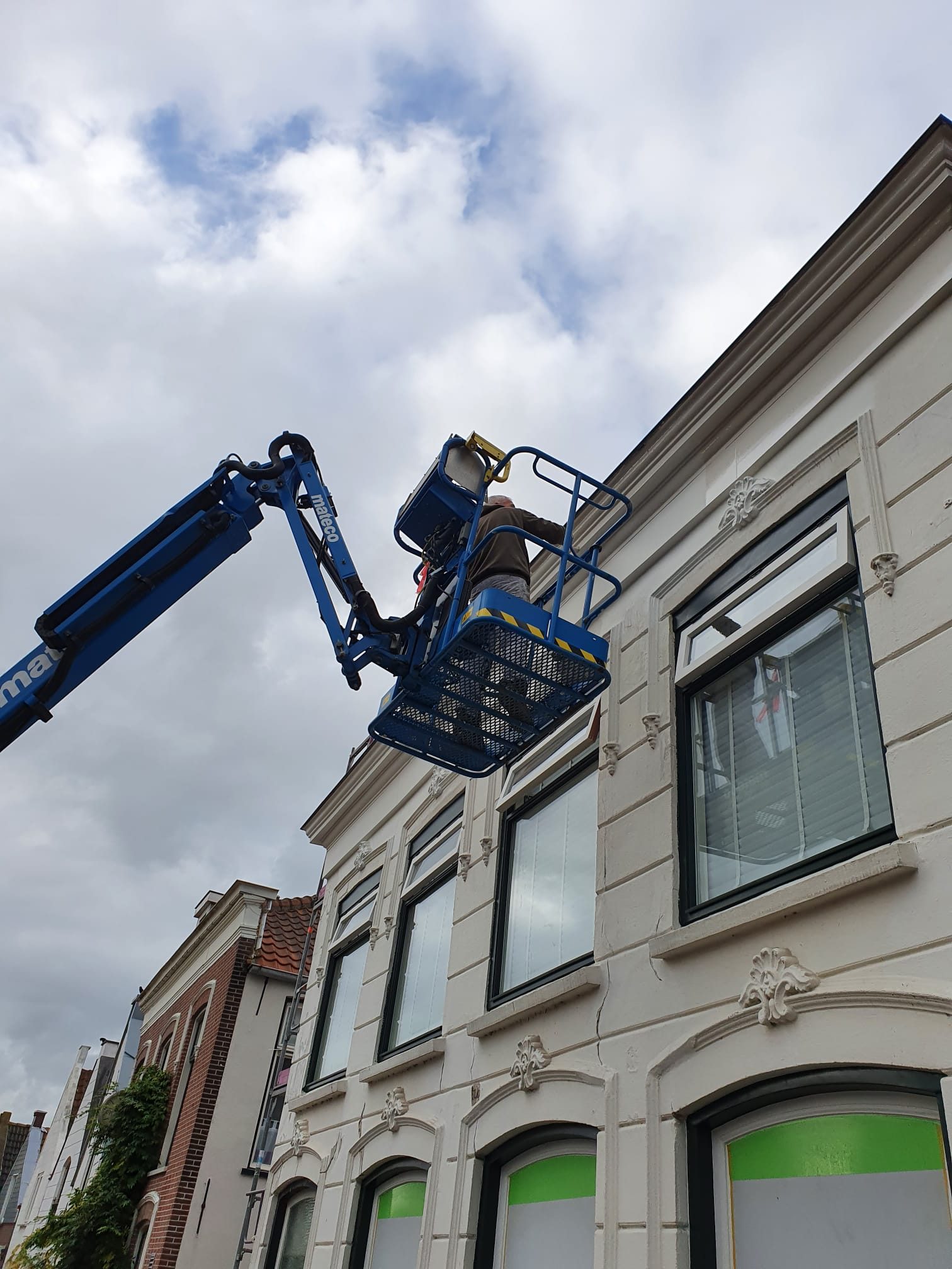Schilder aan het werk vanaf een hoogwerker
